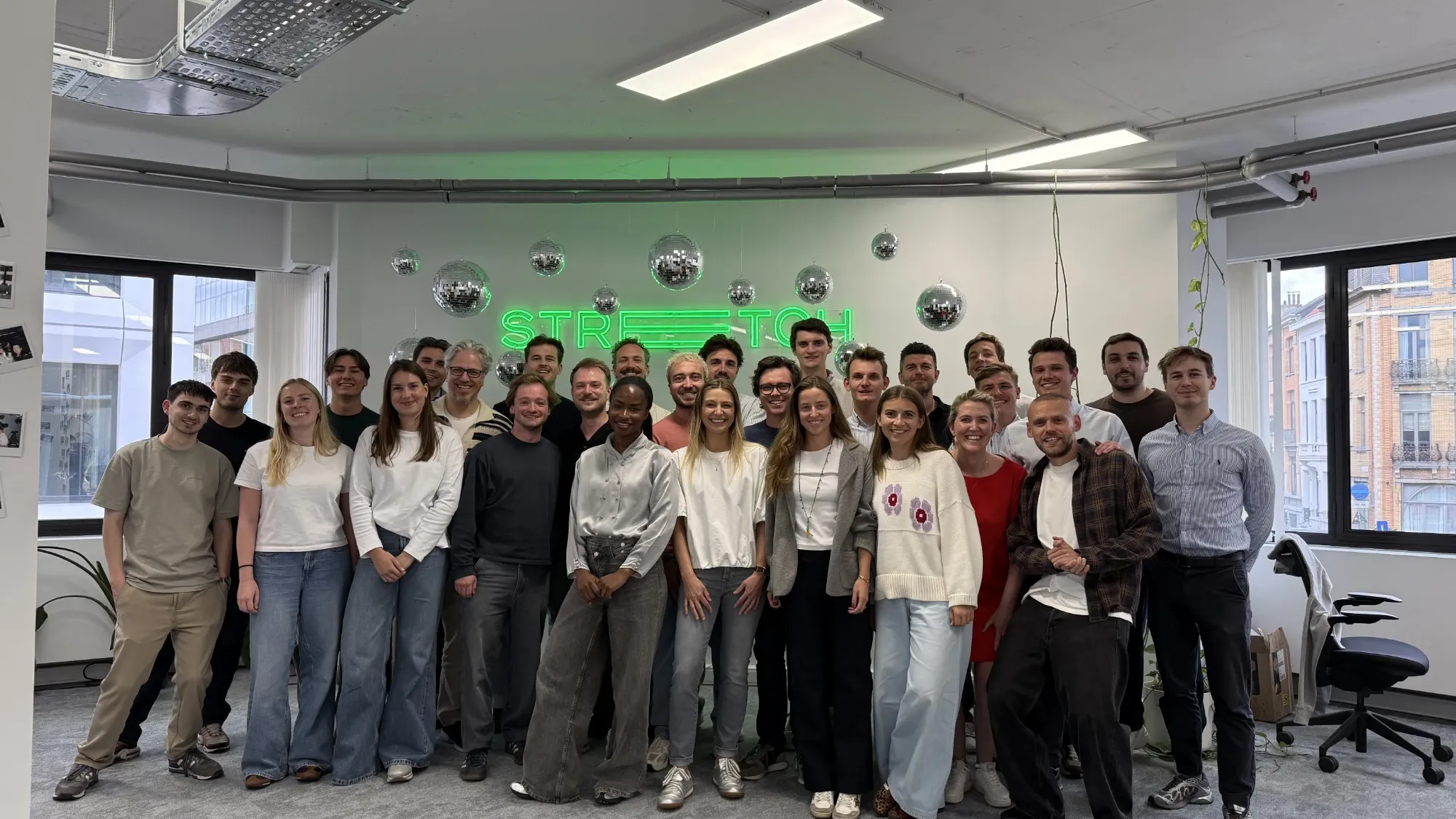 Het team van Stretch Innovation voor het neonlogo in het kantoor in Antwerpen.